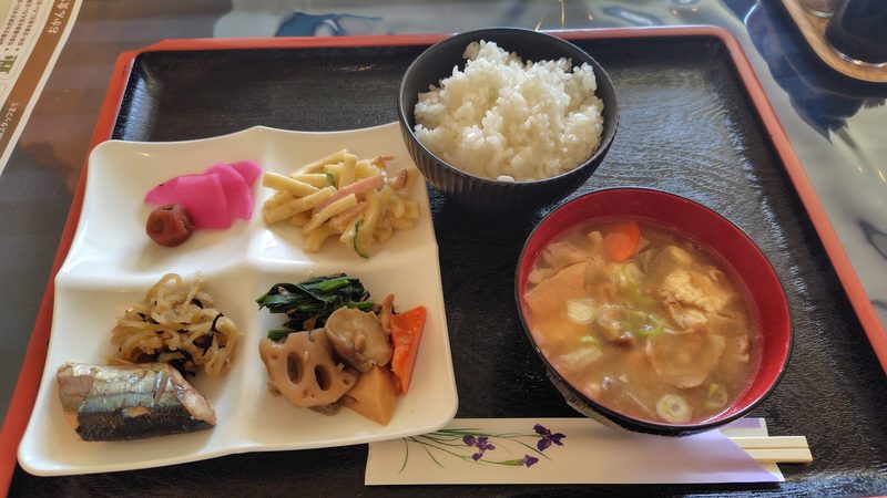 仕切りのある皿に取り分けた何種類ものおかずと、ごはん、具だくさんの汁物