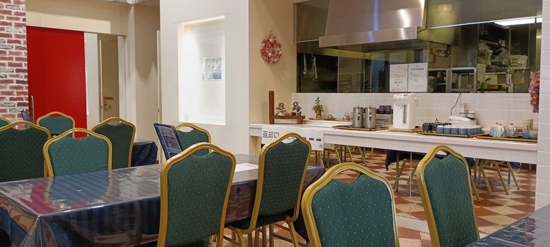 緑の背もたれの椅子とテーブルが並ぶ、明るいおかん食堂の店内