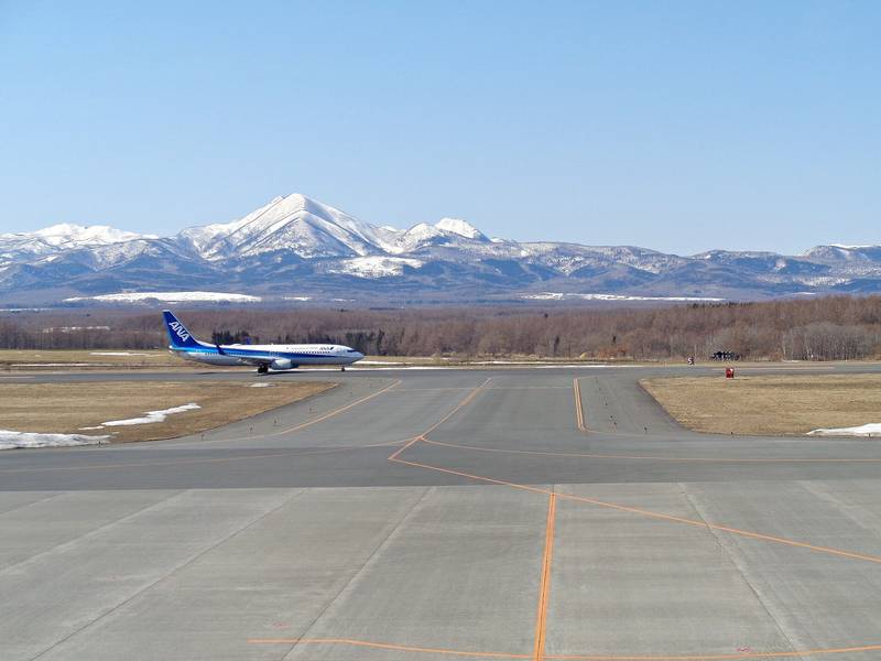 雪をかぶった知床の山々を背に、中標津空港に止まる旅客機